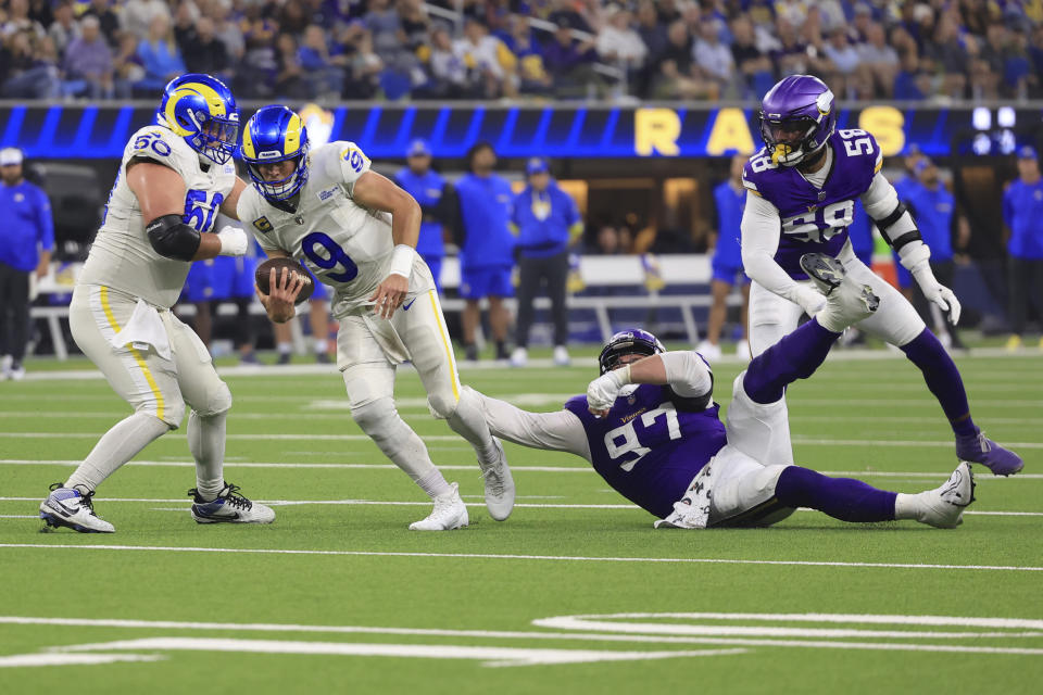 Los Angeles Rams quarterback Matthew Stafford (9) scrambles as Minnesota Vikings defensive tackle Harrison Phillips (97) tries to tackle during the first half of an NFL football game, Thursday, Oct. 24, 2024, in Inglewood, Calif. (AP Photo/Ryan Sun)