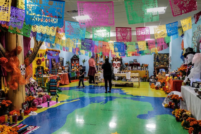 Visitors to the State of Michigan Library look over the Dia de los Muertos ofrendas Friday, Nov. 1, 2024. during a three day event that runs through Sunday. The event is organized by Casa de Rosado Galeria and Cultural Center in Lansing,