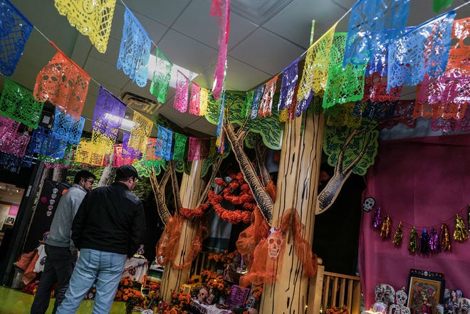 Two men check out the Dia de los Muertos exhibit at the State of Michigan Library and sponsored by Casa de Rosado Galeria and Cultural Center Friday, Nov. 1, 2024.