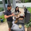 Stoio Kachev and Doanh Nghiem cook dinner outdoors on a large electric grill.