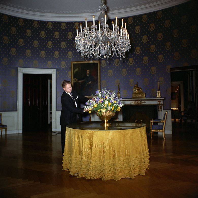 An man arranges flowers in a vase in the Blue Room of the White House in March 1962.