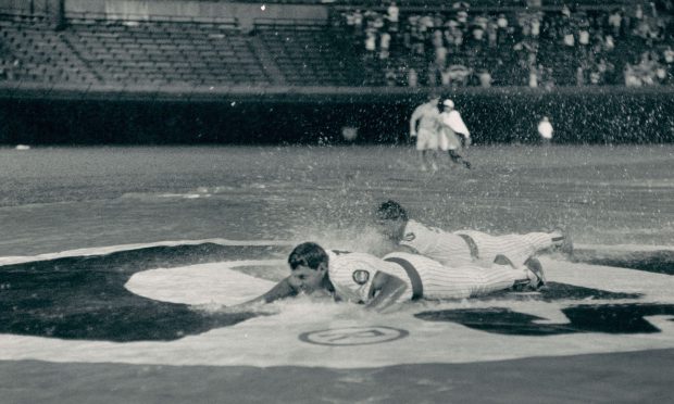 Jody Davis, foreground, and Cubs teammate Les Lancaster take advantage of a rain delay to slide on the tarp Aug. 8, 1988, at Wrigley Field. (Ovie Carter/Chicago Tribune)
