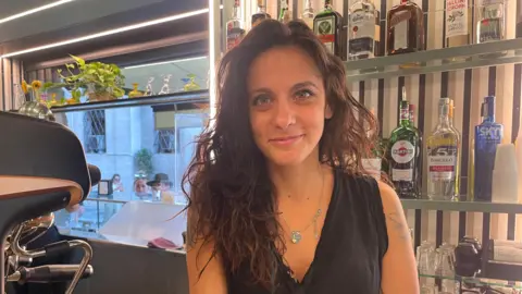 a young woman behind the counter of a cafe