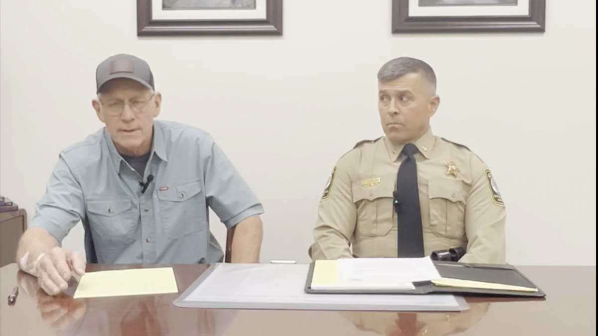 Michael Hatcher, left, seen with a bandage on his right forearm as he speaks with Rockingham County Sheriff Bryan Hutcheson, who is in uniform on the right.