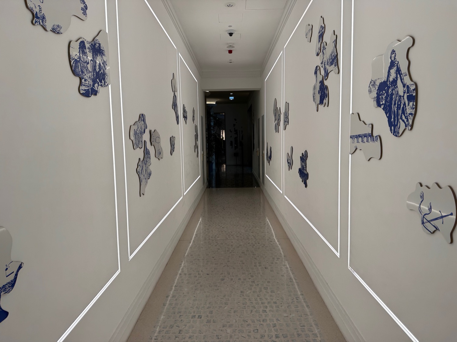 a hallway with white walls and blue and white wall art
