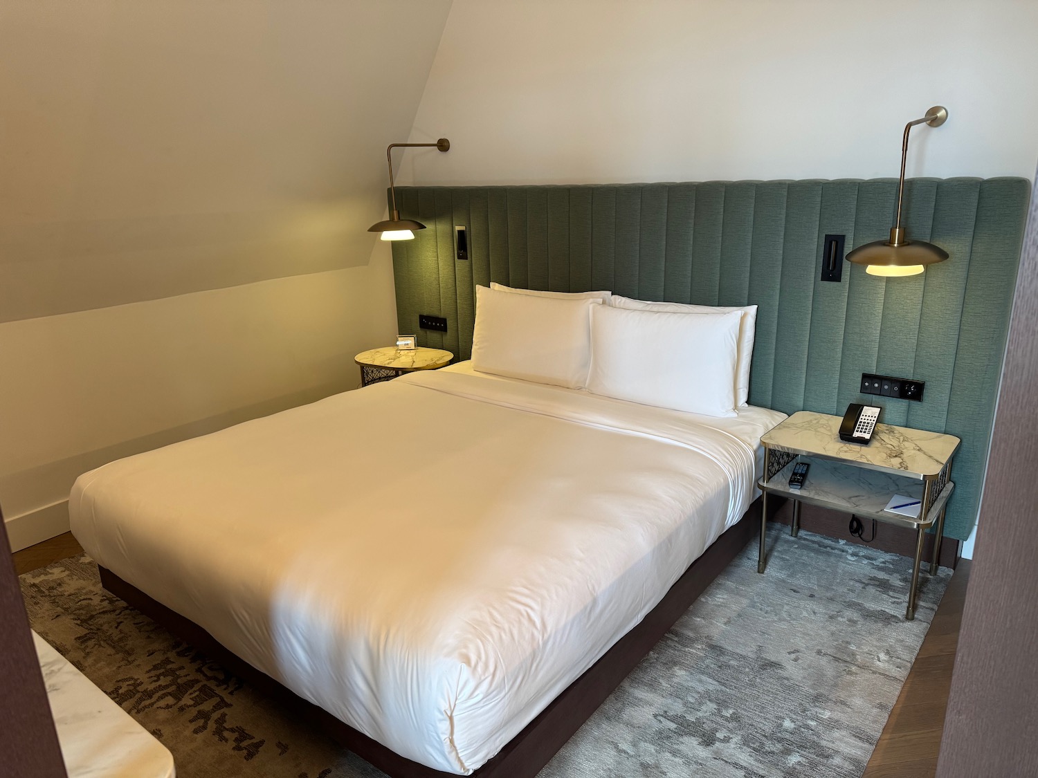 a bed with white sheets and a green headboard