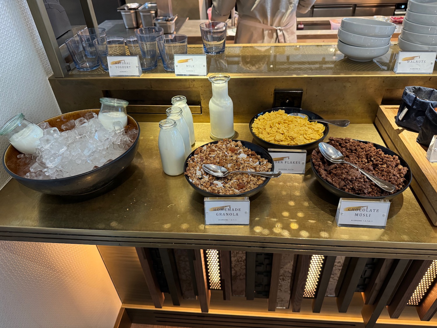 a table with bowls of cereal and ice and milk