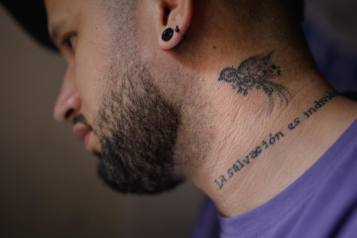 A dark-bearded main with a tattoo of a bird on his neck