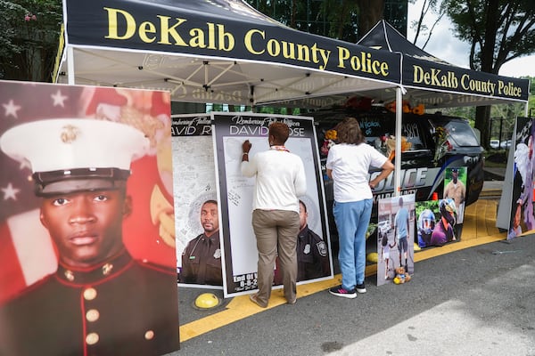 Community members pay their respects at a memorial for Officer David Rose outside of the the DeKalb County Police Department. (Abbey Cutrer / AJC)