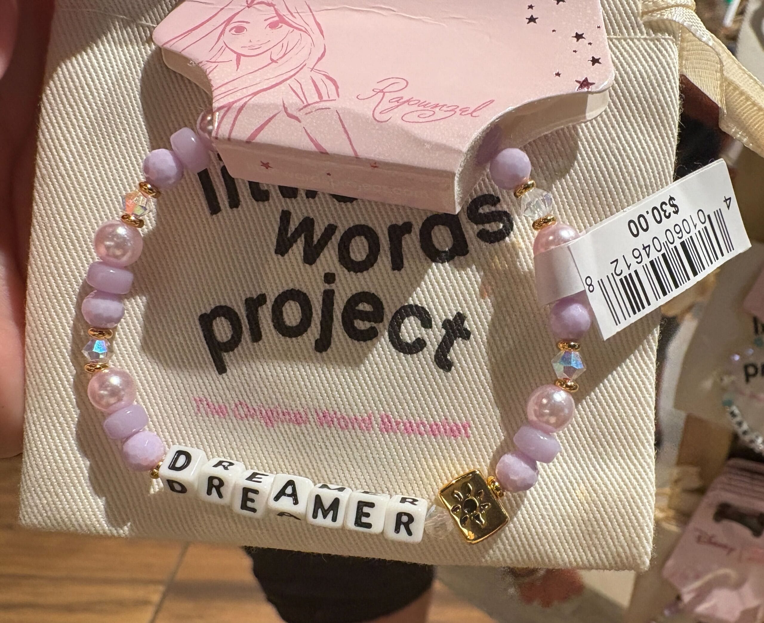A beaded bracelet with “DREAMER” letter beads, displayed on Rapunzel-themed