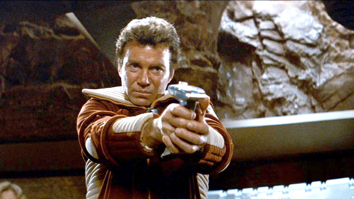 William Shatner holds a weapon in a scene from Star Trek