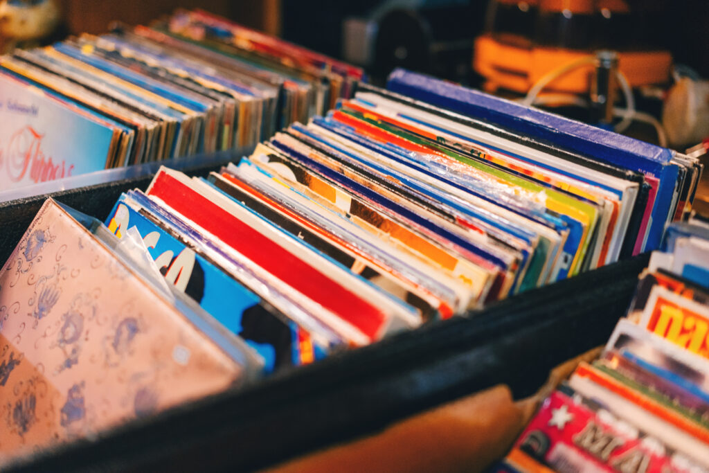 A view of colorful records in milk crate boxes, likely at a vintage record store.