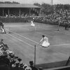 Edith Johnson and Dorothea Lambert Chambers, both wearing ankle-length white dresses, face off on a Wimbledon tennis court in 1910 in this black-and-white photograph.