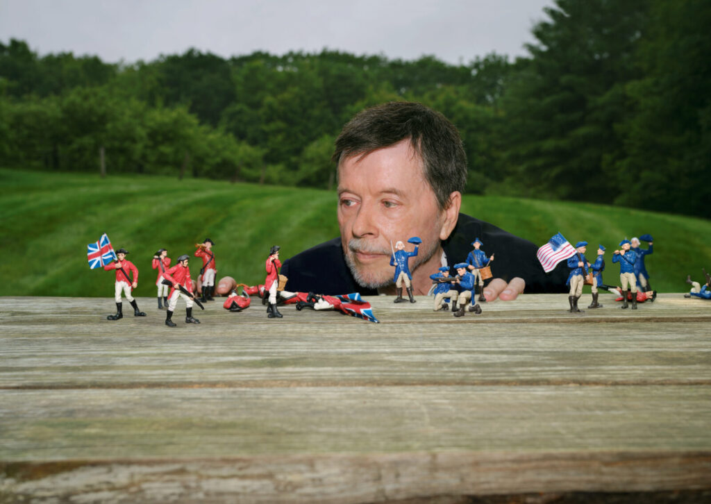 Ken Burns crouches by a table of toy soldiers