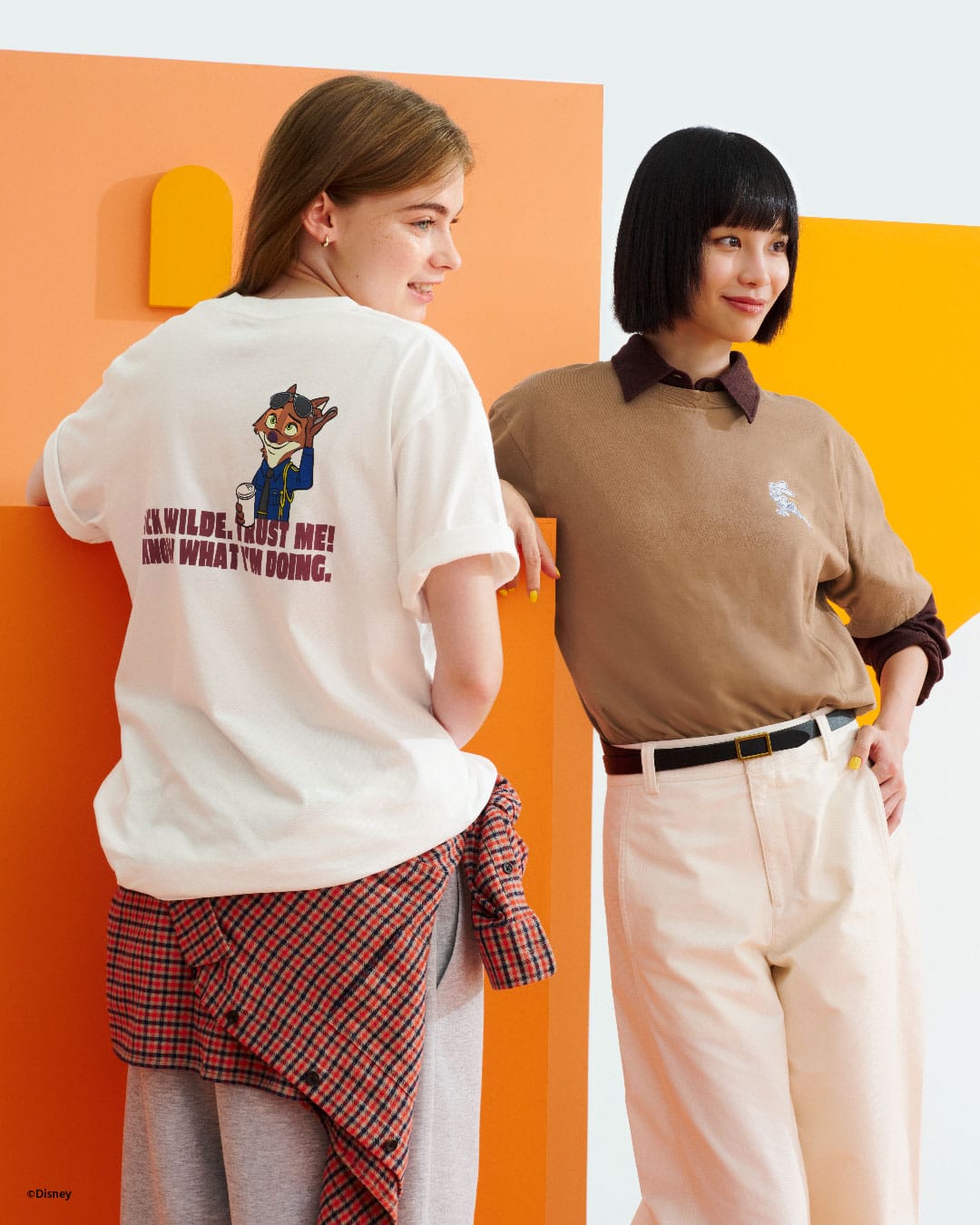 Two women smile at a Disney park; one sports a Nick Wilde shirt from the Disney Store, with no castle visible in the background.