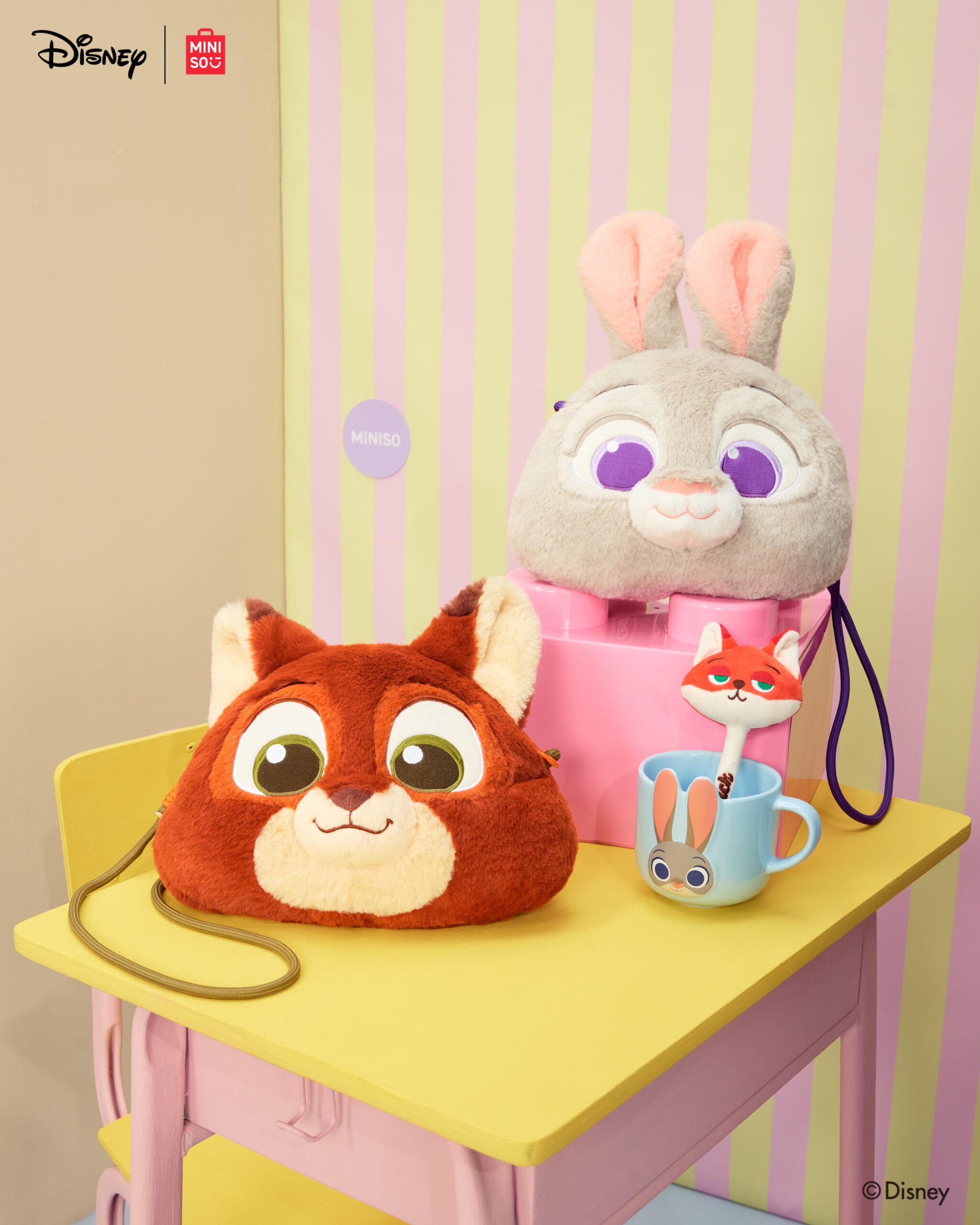 Plush Chip and Judy Hopps bags, Zootopia 2 merchandise, and a Nick Wilde figure displayed on a pastel Disney Parks-themed table.