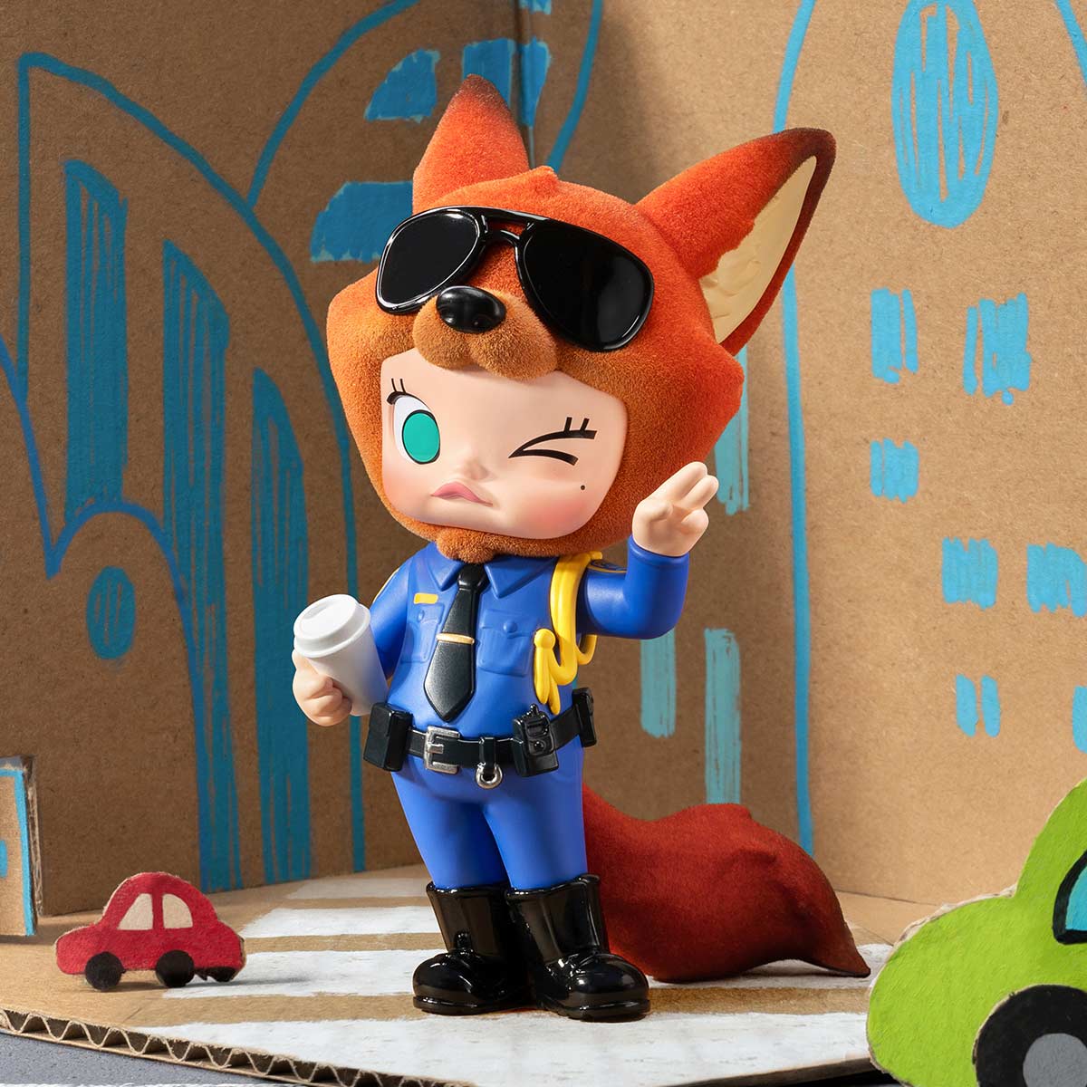 A fox in a police uniform, holding coffee, stands near toy cars—ideal Zootopia 2 merch, reminiscent of Disney park character spots.