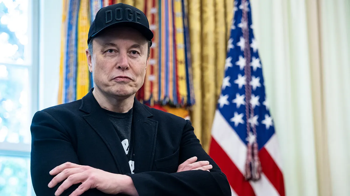 Elon Musk with a US flag behind him.