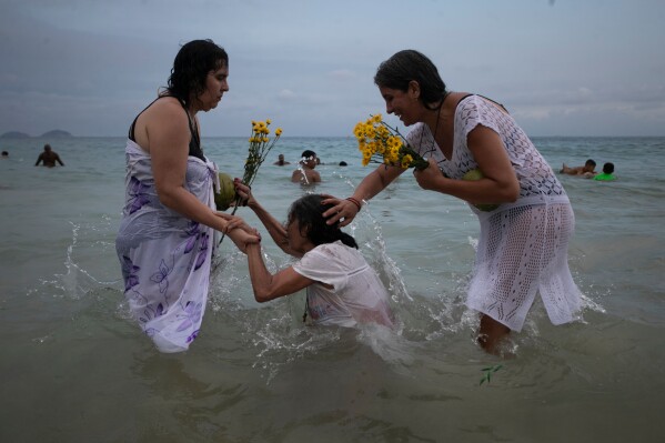 People pray on Copacabana Beach during a ceremony honoring Yemanja, the sea goddess of the Yoruba religion, in Rio de Janeiro, Monday, Dec. 29, 2025. (AP Photo/Bruna Prado)