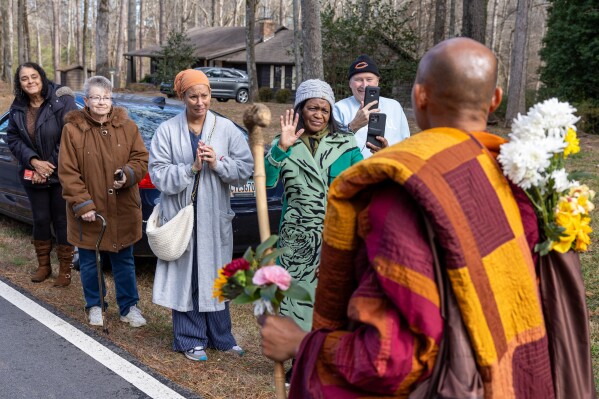People greet Buddhist monks on a 