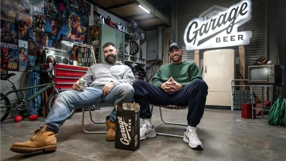 NFL brothers Jason and Travis Kelce sitting in a garage together, surrounded by tools