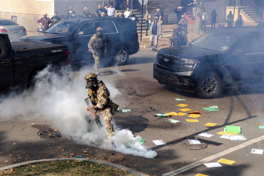 A federal agent prepares to throw a tear gas canister at community members during clashes on Chicago’s South Side, in Chicago, Illinois, on October 14, 2025.