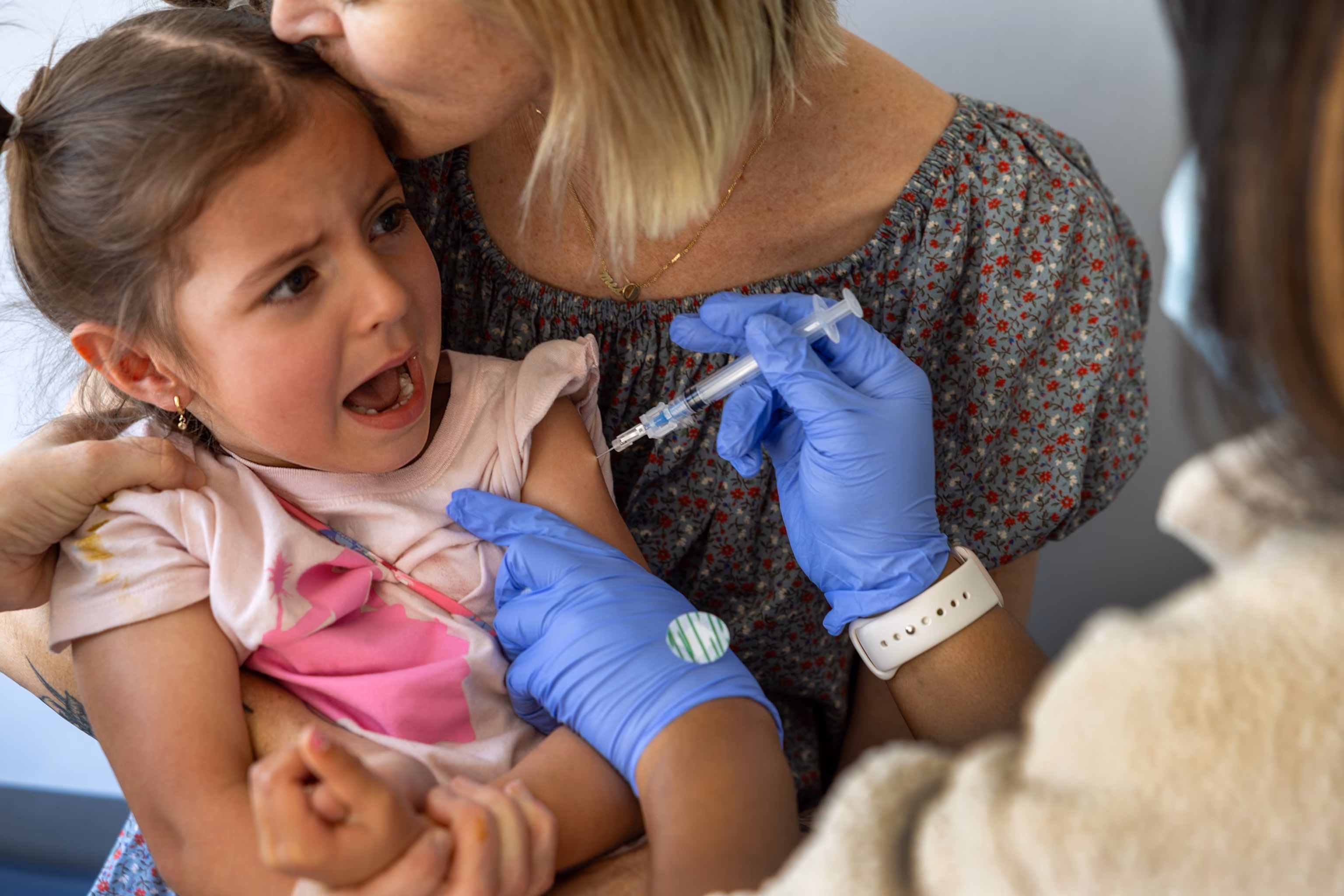 PHOTO: Dr. Neville Anderson, left, helps to hold Iris Behnam, 4, while nurse Breanna Kirby, right, gives her DTap Polio and MMR Chickenpox (Varicilla) vaccinations while her mom, Haley Behnam,in Los Angeles, March 25, 2025. 