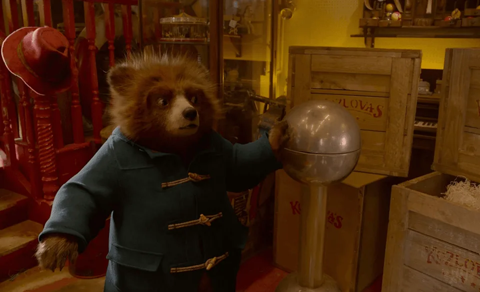 Bear in blue coat touches silver sphere in a cluttered room. | IMDB