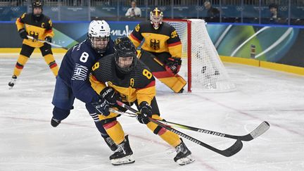 La Française Jade Barbirati au duel avec l'Allemande Ronja Hark lors de la rencontre de hockey sur glace féminin entre les deux équipes le 9 février 2026, aux Jeux de Milan Cortina. (ALEXANDER NEMENOV / AFP)