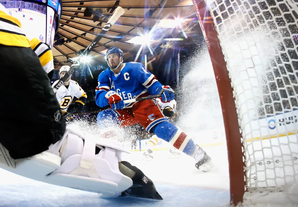 New York Rangers player J.T. Miller skates towards the net with the puck while a Boston Bruins player defends.