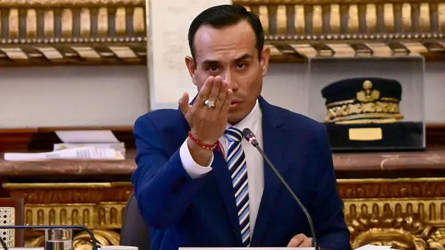 José Jerí habla a un micrófono y eleva su mano derecha. 