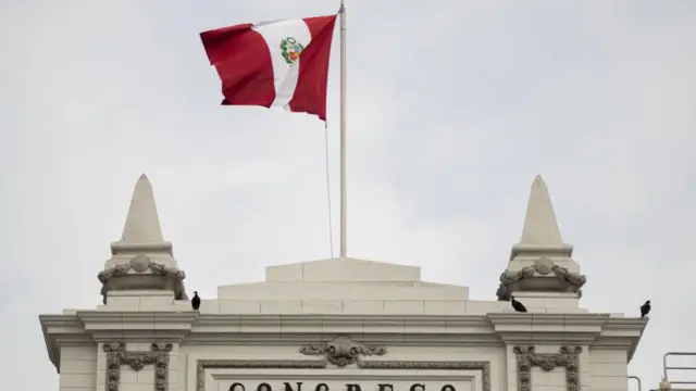 La bandera peruana ondea sobre la fachada principal del Congreso de Perú. 