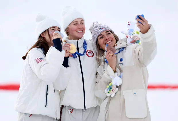 Silver medalist Jaelin Kauf of the United States, from left, gold medalist Elizabeth Lemley of the U.S. and bronze medalist Perrine Laffont of France pose for a victory selfie during the medal ceremony for the women's freestyle skiing moguls at the Milano Cortina Winter Olympics on Feb. 11, 2026, in Livigno, Italy. (Michael Reaves/Getty Images)