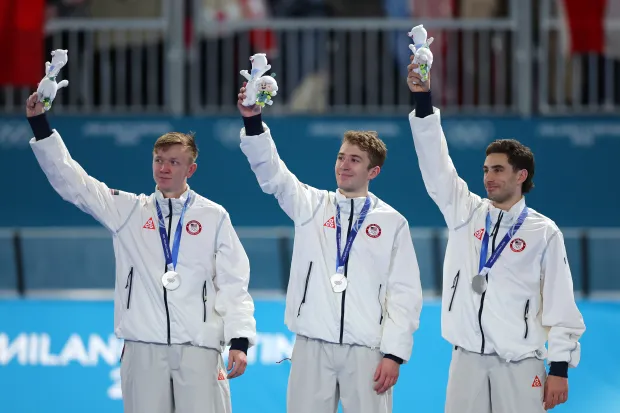 Silver medalist Ethan Cepuran, Casey Dawson and Emery Lehman celebrate on the podium after the team pursuit event on Feb. 17, 2026, in Milan, Italy. (Photo by Elsa/Getty Images)