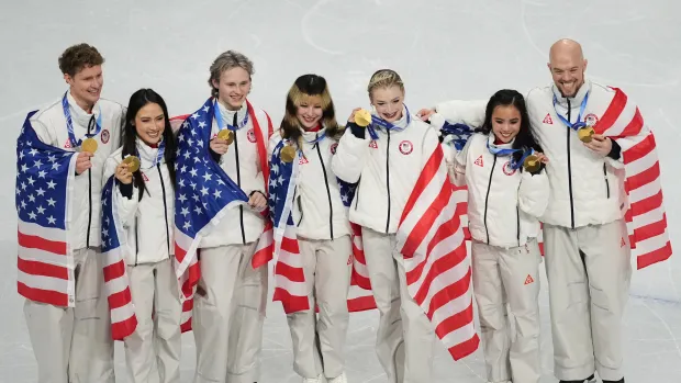 From left, Evan Bates, Madison Chock, Ilia Malinin, Alysa Liu, Amber Glenn, Ellie Kim and Danny O'Shea of Team USA celebrate winning the gold medal in the figure skating team event at the 2026 Winter Olympics on Sunday, Feb. 8, 2026, in Milan. (AP Photo/Natacha Pisarenko)