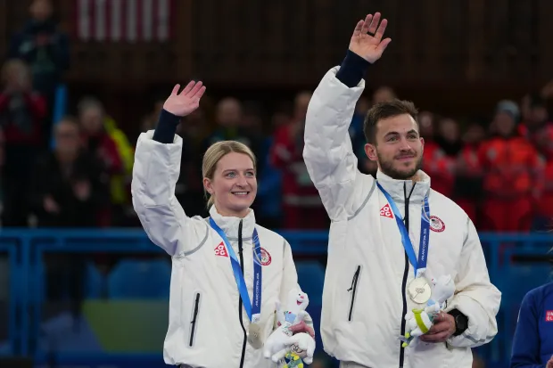The United States' Cory Thiesse and Korey Dropkin wave on the podium after winning the silver medal in mixed doubles curling at the 2026 Winter Olympics on Tuesday, Feb. 10, 2026, in Cortina d'Ampezzo, Italy. (AP Photo/Misper Apawu)