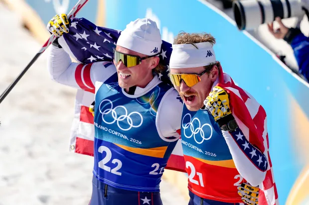 Ben Ogden, right, and Gus Schumacher celebrate after winning the silver medal in the cross-country skiing men's team sprint free in Tesero, Italy, on Feb. 18, 2026. (AP Photo/Matthias Schrader)