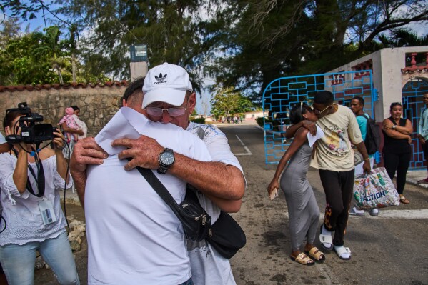 A pardoned prisoner, wearing cap, hugs a family member, as another kisses a woman after their release from La Lima penitentiary in Guanabacoa, Havana, Cuba, Friday, April 3, 2026. (AP Photo/Ramon Espinosa)