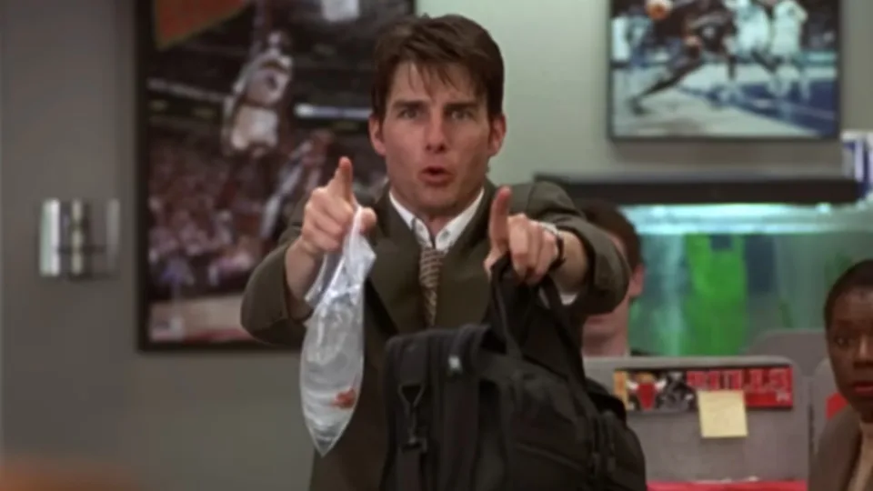 Tom Cruise pointing and yelling while holding a bag with a fish in it in his left hand and a breif case in his right hand in Jerry Maguire. 