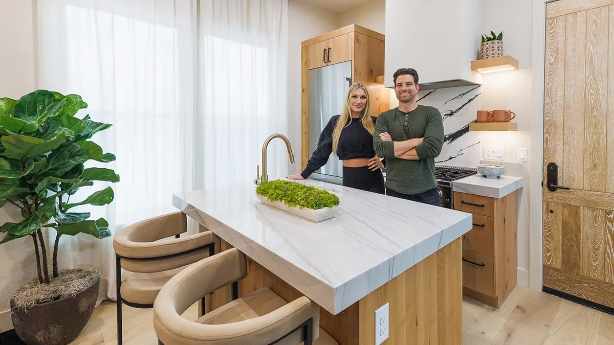 Brooke Hogan and Steve McGillivray standing behind a marble kitchen island in a renovated suite.