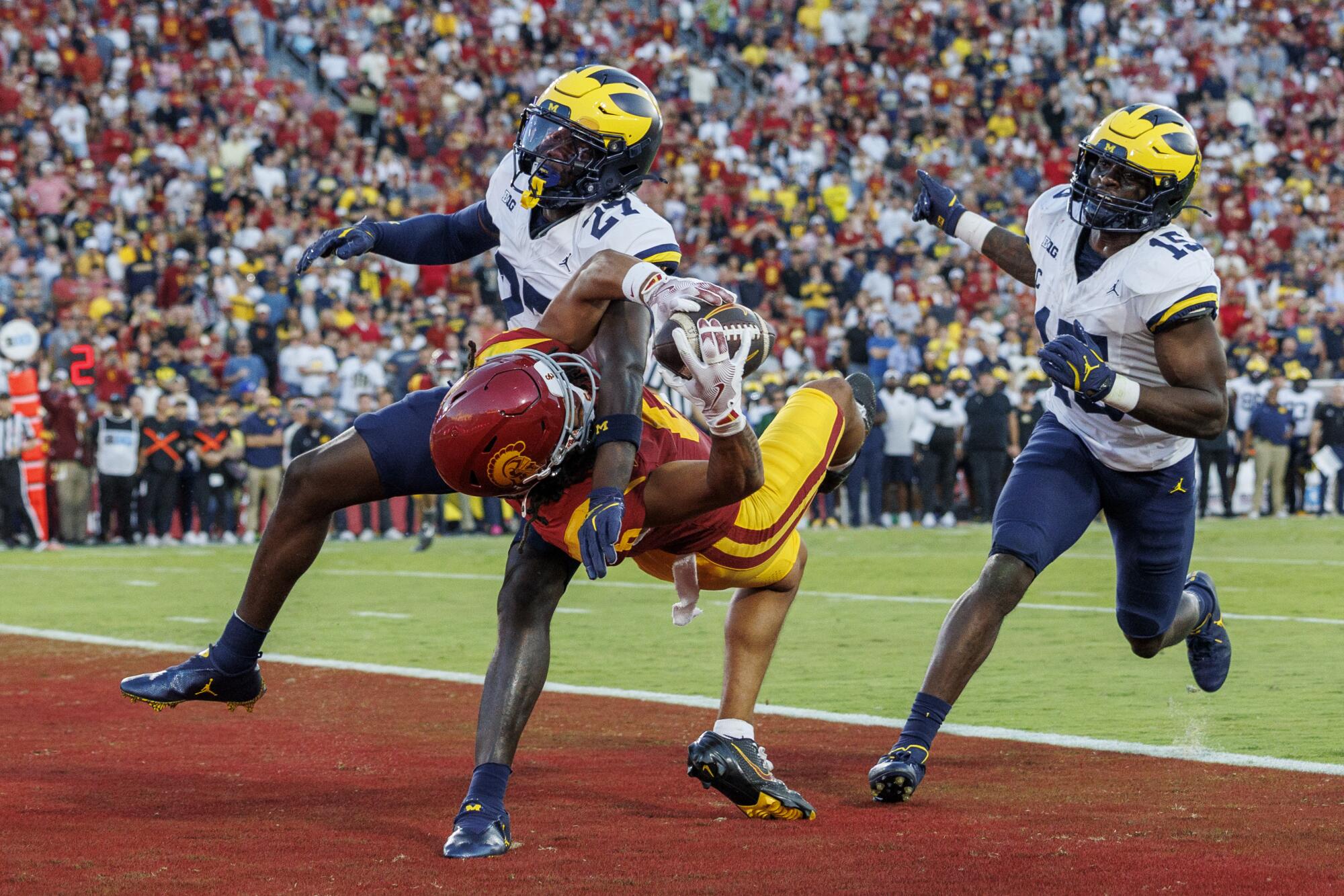 USC receiver Makai Lemon falls backward while making an acrobatic touchdown catch in front of Michigan's Jayden Sanders.