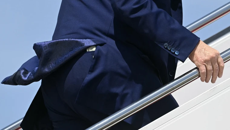 A 50 dollar bill poking up from a seat pocket in President Trump's pants as he ascends the stairs to Air Force One.