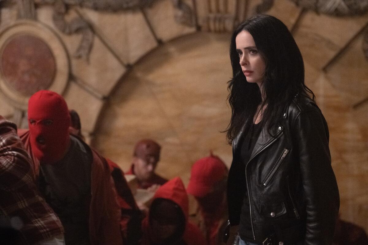 Jessica Jones stands near a masked mob