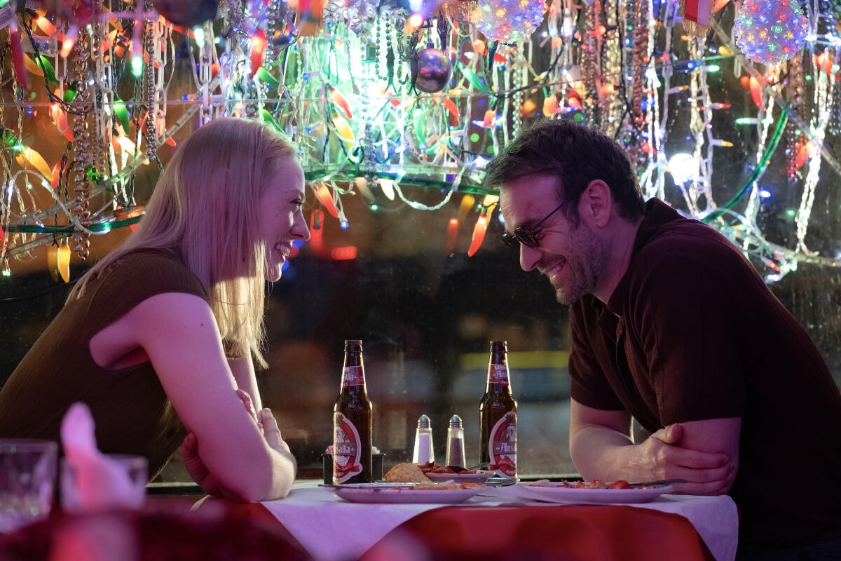 Karen Page and Matt Murdock sitting at a restaurant table surrounded by lights