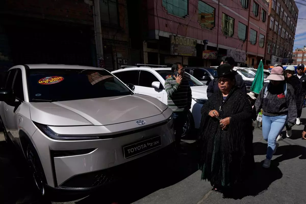 People walks past electric cars displayed for sale at