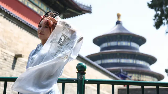 北京天坛公园外一位身穿传统汉服的女子摆出姿势拍照留念（12/5/2026）