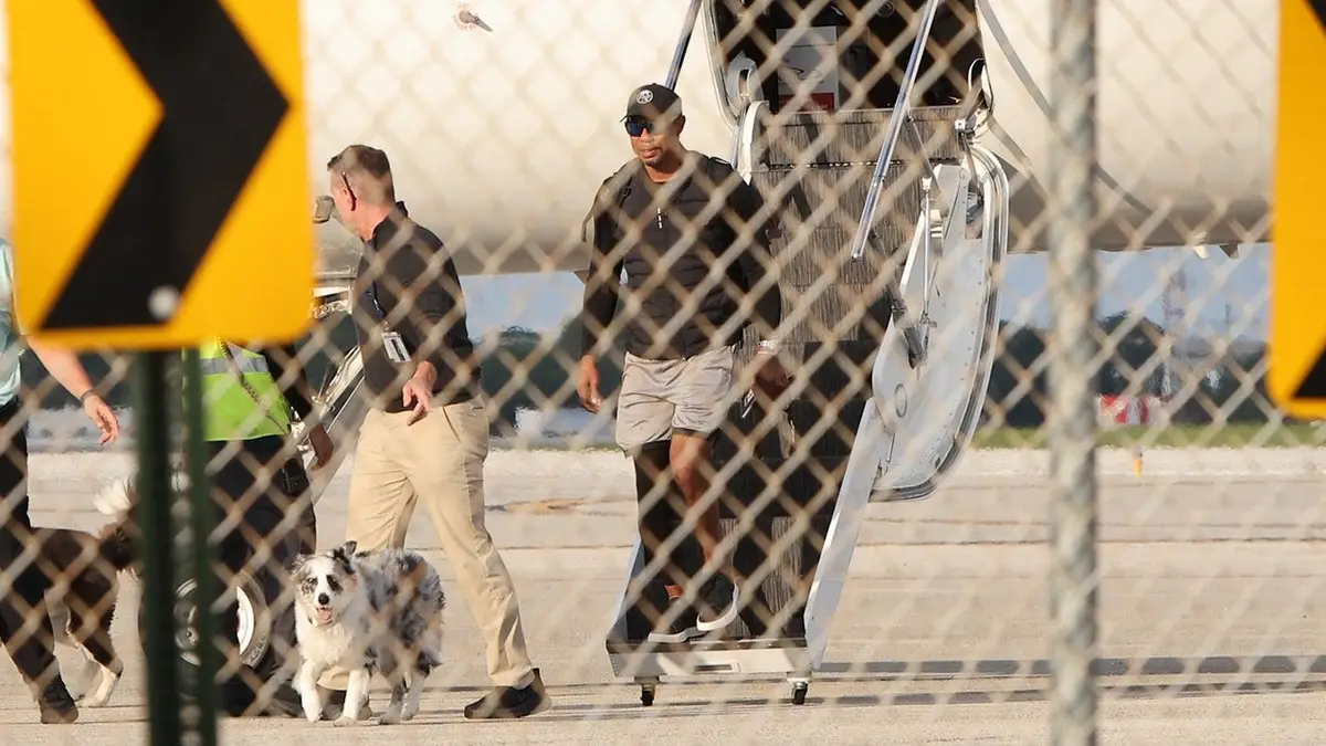 Tiger Woods walking on a tarmac near a private plane in Palm Beach Florida