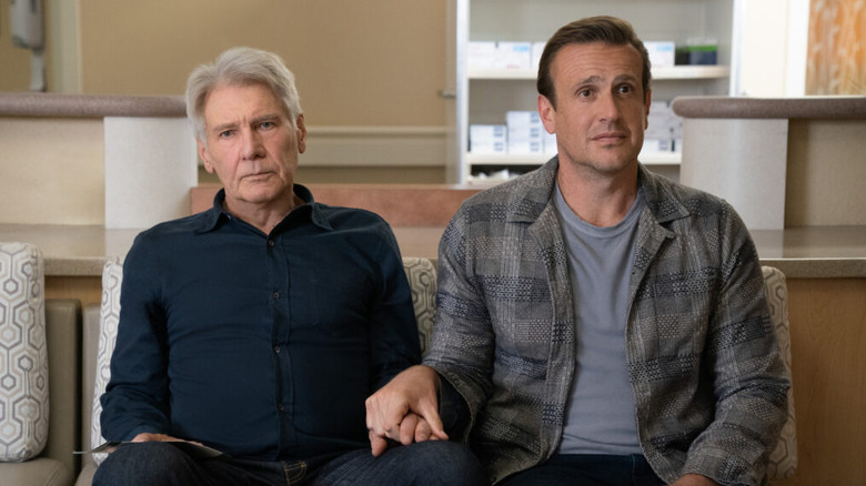 Dr. Rhoades and Jimmy Laird holding hands on a couch in Shrinking