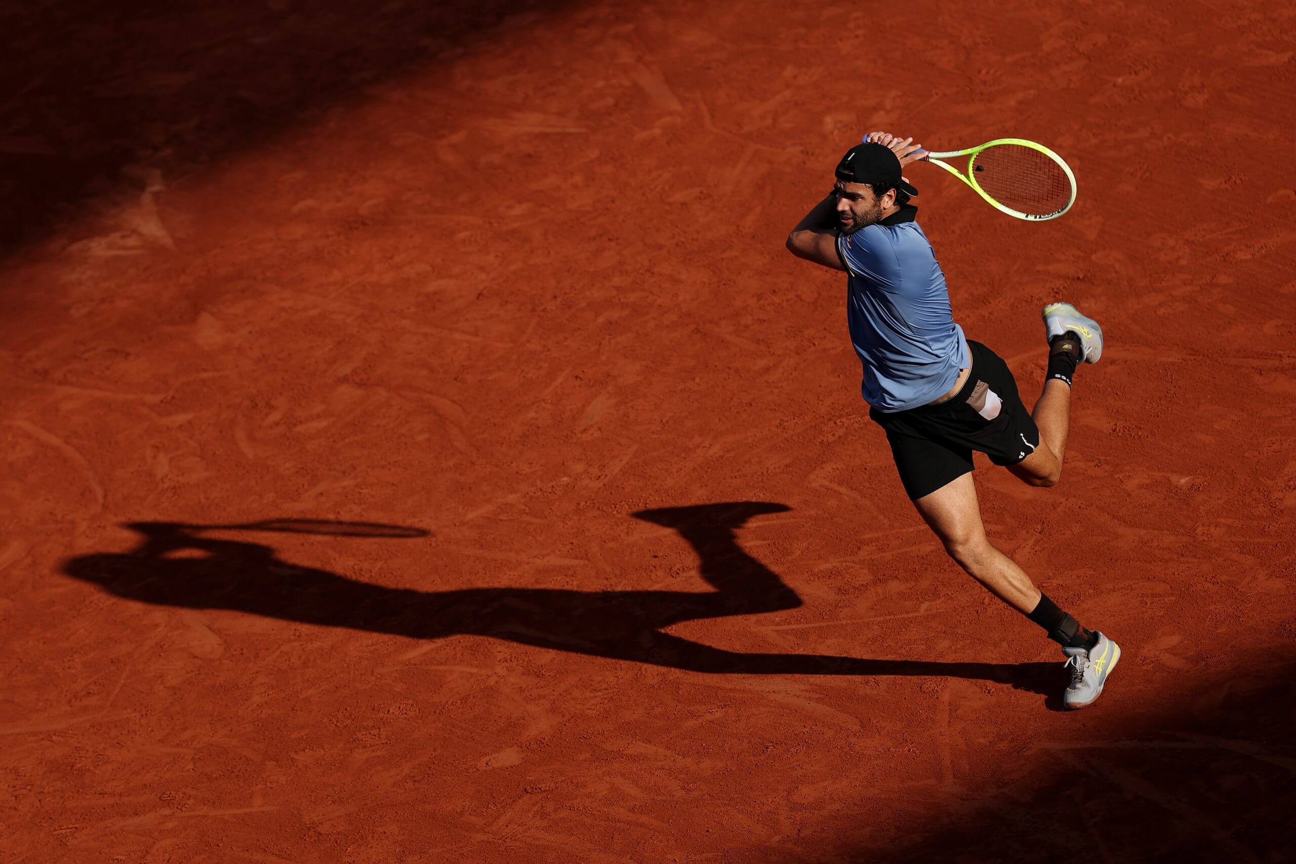 Matteo Berrettini hits a two-handed backhand on a clay court.