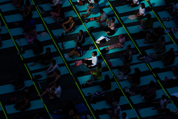 People participate in a mass yoga class during the 